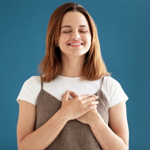 Woman ponders with hands on heart and eyes closed