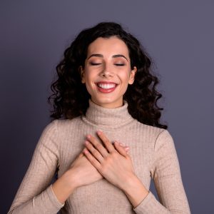 Happy woman with hands over heart